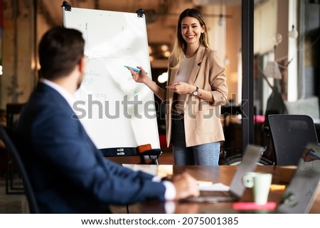Businesswoman present her idea to working team. Young happy woman presenting businessplan Royalty-Free Stock Photo #2075001385