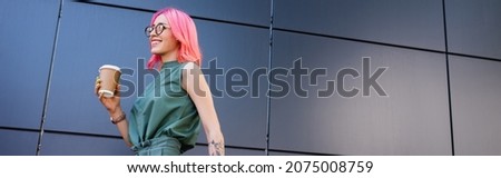 happy and tattooed businesswoman with pink hair holding paper cup outside, banner