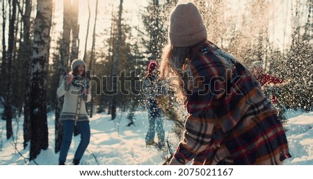 Happy diverse friends enjoy fun snowball fight at sunny winter forest with dog on New Year vacation together slow motion Royalty-Free Stock Photo #2075021167