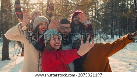 New Year holidays. Group of happy fun multiethnic friends take selfie photo at amazing snowy winter forest slow motion.