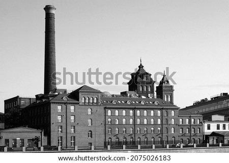 Old factory building, built in the 19th century of brick with a high chimney. Black and white photo Royalty-Free Stock Photo #2075026183
