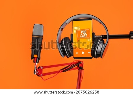 Modern microphone with headphones and mobile phone with with podcast playlist on screen against color background Royalty-Free Stock Photo #2075026258