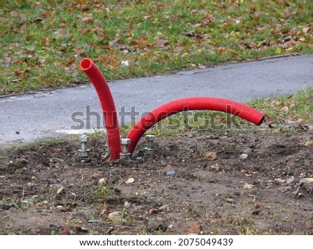 Tubes look like worms.Powerful foundation bolts and corrugated red pipes for laying power cable. Street lighting pole mounting technology. Сoncept of urban environment improvement.
