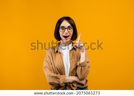 Great idea, inspiration concept. Excited caucasian lady having wow creative idea, raising finger up and looking at camera, standing over orange studio background Royalty-Free Stock Photo #2075065273