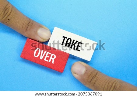 hand pointing at a colored board with the word Take Over Royalty-Free Stock Photo #2075067091