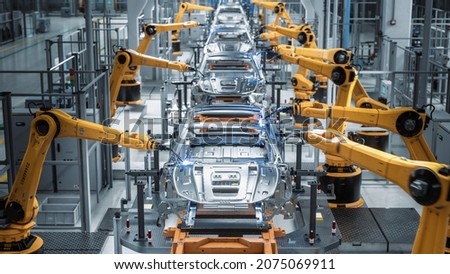 Car Factory 3D Concept: Automated Robot Arm Assembly Line Manufacturing High-Tech Green Energy Electric Vehicles. Automatic Construction, Building, Welding Industrial Production Conveyor. Front View Royalty-Free Stock Photo #2075069911