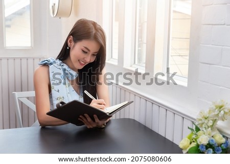 Asian woman writing on notebook at the home office for setting challenging business goals And planning to achieve the new target.