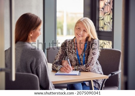 Smiling Female University Or College Student Having Individual Meeting With Tutor Or Counsellor Royalty-Free Stock Photo #2075090341
