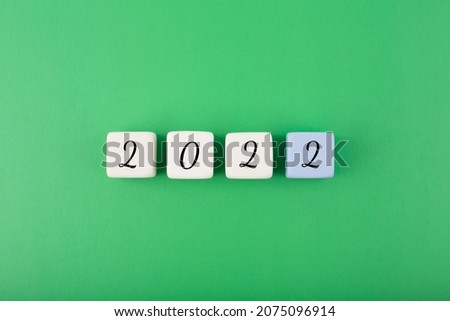 2022 numbers on white cubes against green background. Minimal elegant business style concept of New Year 