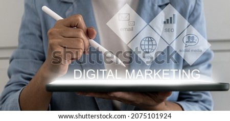 A person holding a tablet and pen pointing at a screen labeled "digital marketing" and showing a visual icon about online marketing. Digital marketing concept.