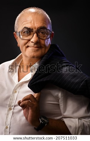Closeup portrait of stylish mature man in white shirt, holding jacket over shoulder, smiling, looking away.