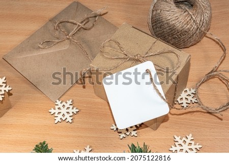 Gifts in craft paper with twine bows, blank labels on the table with wooden snowflakes. Zero waste Christmas concept.