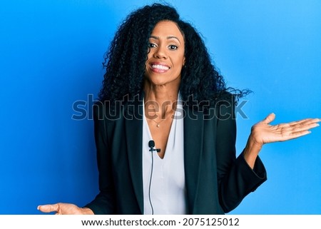 Middle age african american woman using lavalier microphone celebrating achievement with happy smile and winner expression with raised hand 