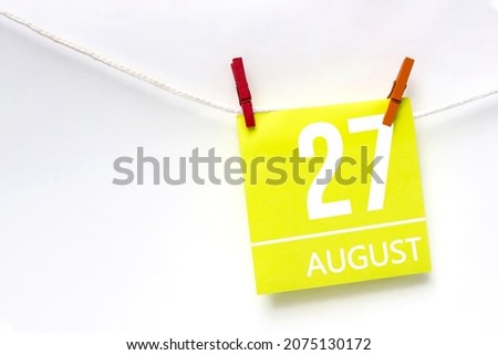 August 27th. Day 27 of month, Calendar date. Paper cards with calendar day hanging rope with clothespins on white background. Summer month, day of the year concept