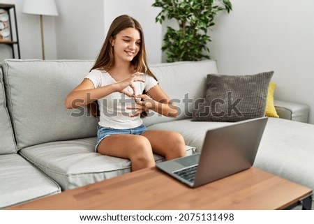 Adorable girl having video call communicating with deaf language sitting on sofa at home