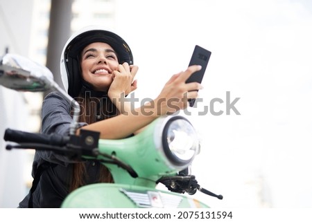 Beautiful woman getting ready for a ride on scooter. Beautiful happy lady taking selfie photo.	