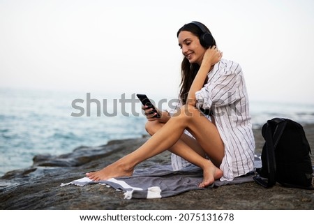 Hot woman relaxing on the sandy beach. Beautiful woman with headphones listening the music	