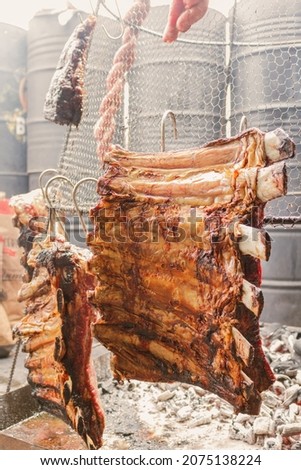 pork ribs suspended on top of a grill Royalty-Free Stock Photo #2075138224