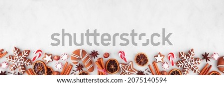 Christmas baking bottom border with cookies, peppermints and spices. Top view over a white marble background with copy space. Holiday baking concept.