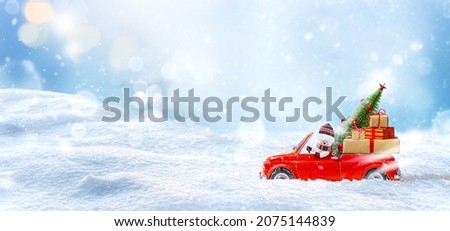 Snowman in Red car delivering christmas tree and presents at winter snow background.