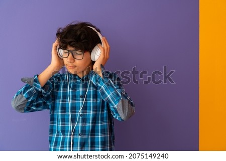 Teenage Boy Wearing Headphones And Listening To Music purple background