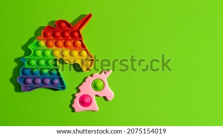 Two antistress fidgets - pop it and simple dimple on the green background.New sensory antistress toy for children and adult.Trendy rainbow coloring,large banner.