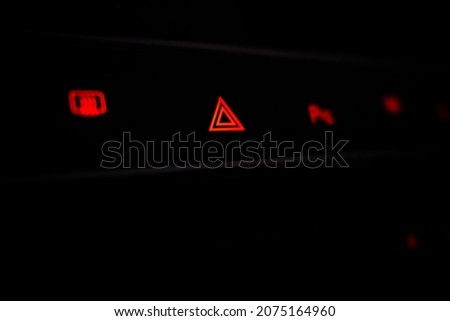 Red triangle emergency stop symbol. Control panel with red night illumination in the car. Buttons with red symbols in the car interior.