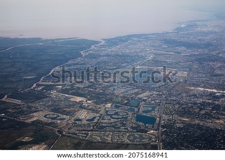 Flying over Buenos Aires. Cityscape. Aerial view of the city from an airplane. The town buildings, houses, streets and Rio de la Plata, under a blue sky. Beautiful urban texture and pattern.	