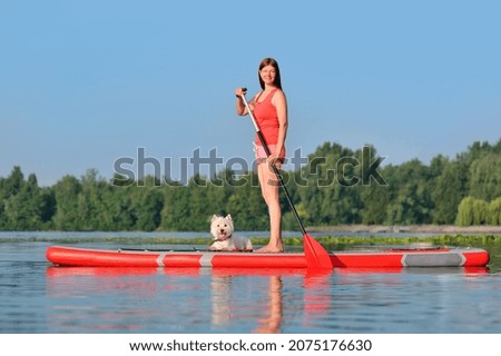 Full length picture of a woman standing on the sup board