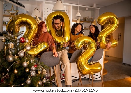 Group of young beautiful people in casual clothing carrying gold colored numbers and smiling Royalty-Free Stock Photo #2075191195