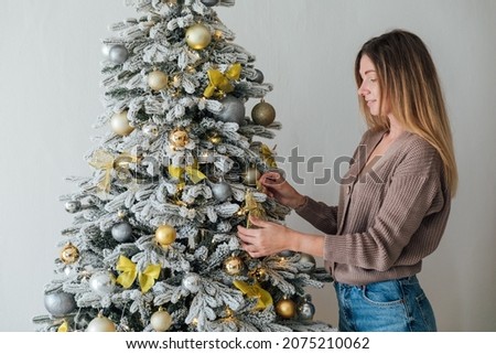 beautiful woman decorates a white Christmas tree new year gifts decor