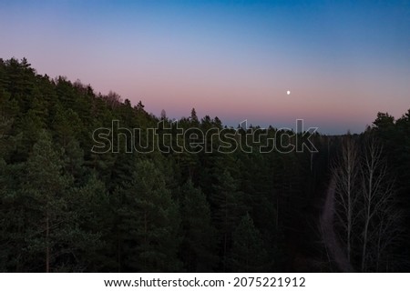 Bird's-eye view of a scenic sunset over the forest hills, with toned dramatic colors