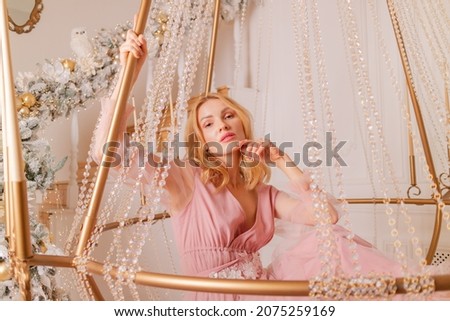 beautiful blonde in a long pink dress in a beautiful interior of a photo studio