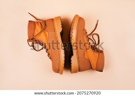 Trendy fall fashion flatlay with cozy brown suede boots isolated on beige background.