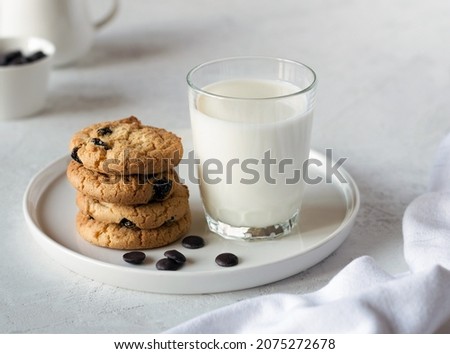 Delicious cookies with chocolate on a white plate and fresh milk in a glass on a light table. An idea for a children's breakfast or snack. Selective focus Royalty-Free Stock Photo #2075272678