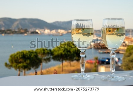 Summer on French Riviera, drinking of cold white wine from Cotes de Provence on outdoor terrase with view on harbour of Toulon, Var, France