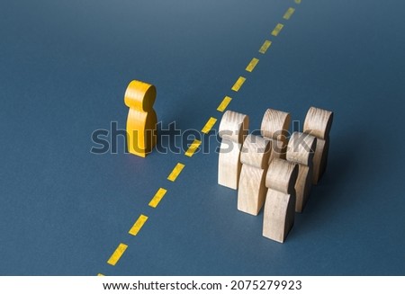 A person and a group of people are separated by a yellow line. Establishing contact. Distrust. Quarantine. Distance with strangers. Barrier to understanding, difficult integration. Rejection, refusal. Royalty-Free Stock Photo #2075279923
