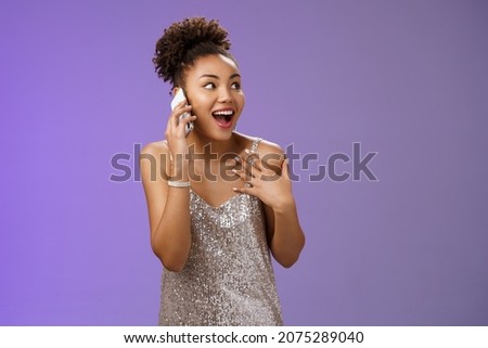 Impressed sociable african-american talkative woman in silver dress talking smartphone pointing herself amused describing emotions impressions after visit awesome party, blue background Royalty-Free Stock Photo #2075289040