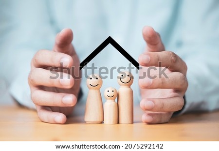 Businessman two hands protecting family wooden model for insurance and assurance life concept. Royalty-Free Stock Photo #2075292142