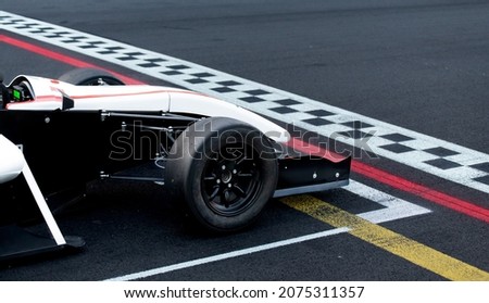 Race start first place concept, formula car nose detail on asphalt racetrack with checkered line Royalty-Free Stock Photo #2075311357