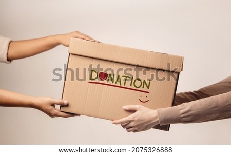 Donation Concept. The Volunteer Giving a Donate Box to the Recipient. Standing against the Walll Royalty-Free Stock Photo #2075326888