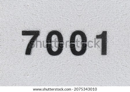 Black Number 7001 on the white wall. Spray paint. Number seven thousand one.
