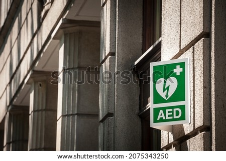 Electric defibrillator logo on a sign in an urban environment, abiding by European standards, indicating the nearby presence of AED device, an obligation to deal with cardiac diseases and heart attack Royalty-Free Stock Photo #2075343250