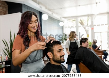 Man getting a haircut from a hair stylist at a barber shop Royalty-Free Stock Photo #2075358466