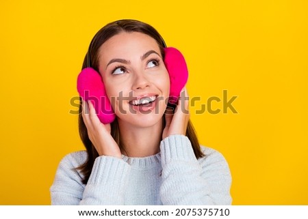 Photo of happy positive dreamy young woman wear earmuff look empty space isolated on yellow color background