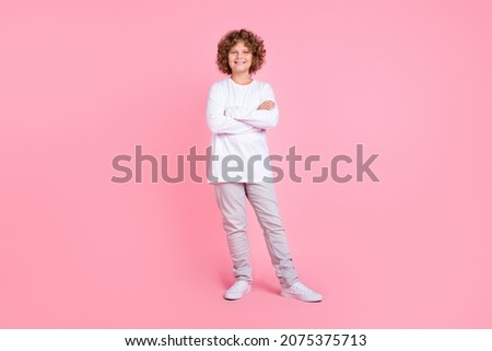 Full length photo of happy cheerful small child hold hands crossed enjoy isolated on pink color background