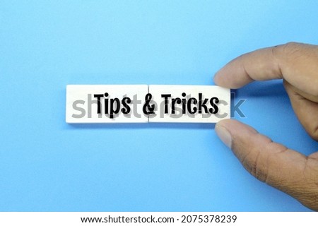 hand holding a colored board with the words Tips and Tricks