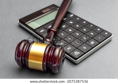 Judge gavel with calculator on grey background.