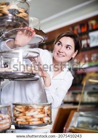 .Young female client choosing delicious dessert in confectionery.