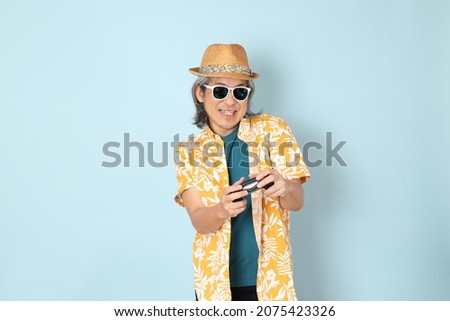 The senior Asian man wearing summer dressed standing on the blue background.